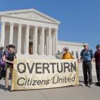 Protesters stand in front of the US Supreme Court holding a sign that says "Overturn Citizens United".