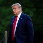Donald Trump walking with trees in the background.