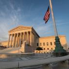 The U.S. Supreme Court in the late afternoon light with an American flag flying next to it