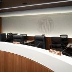 Chairs behind a desk with a large logo of the FEC on the wall behind them