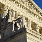 A statue in front of the columns of the Supreme Court building
