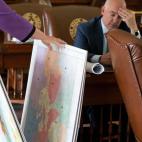 A woman sorts through a stack of large poster prints of maps