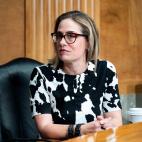 Kyrsten Sinema sitting at a desk looking sideways at the camera