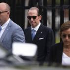 A man in a suit wearing sunglasses with other people around him also wearing sunglasses