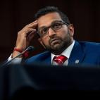 Kash Patel sitting at a desk with his hand raised to his forehead