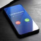 A smartphone on a desk with the words "Unknown, Potential Spam" on the screen and green and red buttons to decline or accept the call.