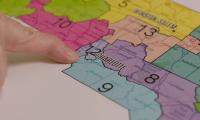 A finger pointing to a district on a map of North Carolina
