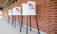A row of voting booths outside along a brick wall