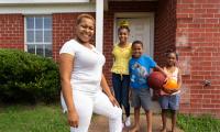 Latoya Slater in front of her house with her three children in the background