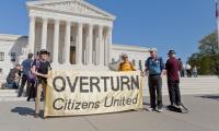 Protesters stand in front of the US Supreme Court holding a sign that says "Overturn Citizens United".