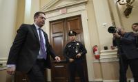 Devin Nunes walking down a hall being photographed by a photographer with a cop in the background