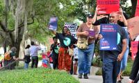 People walk along a path carrying signs