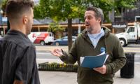 A man with a folder speaking to another man