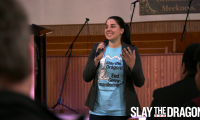 Katie Fahey wearing a t-shirt that says "Slay the Dragon, End Gerrymandering" while speaking in front of a group of people