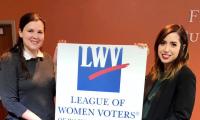 Bonnie Miller and co. hold up a League of Women Voters Sign. 