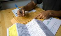 Shot of a person's hands at a table filling out an absentee ballot