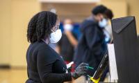 A woman in a face mask and gloves using a screen