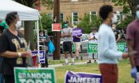 People lined up to vote, some out of focus int he foreground