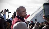 John Lewis in a crowd of people pointing cell phones and cameras at him