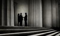 Silhouettes of three figures meeting among a group of columns