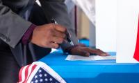 Hand of voter with a pen filling out a ballot