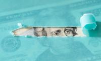 Andrew Jackson on the twenty dollar bill visible through a torn piece of turquoise paper