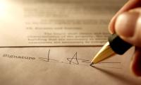 Close up of a person signing a document with a pen