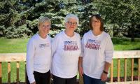 Three women standing on a porch wearing long-sleeved t-shirts which say "Badass Grandmas"