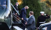 Donald Trump wearing a mask while descending the steps of a helicopter