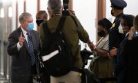 Lindsey Graham wearing a mask and gesturing while speaking to a densely packed group of reporters