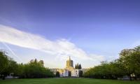 Wide shot of the state capitol building surrounded by green trees and lit with the morning sunlight.