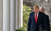 Donald Trump walks along a row of columns with Mike Pence behind him.