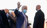 Joe Biden wearing a mask and waving as he gets out of a car