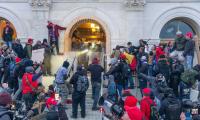 People crowd around an arch doorway while police defend the building