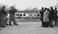 John Lewis and other protestors standing in a group on one side and state troopers walking towards them from the other side