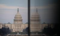 A dark hazy shot of the capitol building seen next to its reflection in another building.