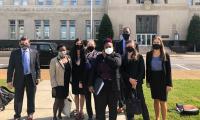 A group of people wearing masks standing in front of a courthouse.