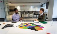 Chris Lamar sitting in front of a table talking with Matthew Petering. On the table there is a large map of Wisconsin between them.