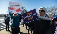 People in winter clothes hold signs that say "End Gerrymandering Now"