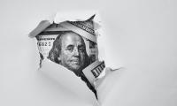 A $100 bill seen through torn white paper