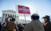 People in front of the Supreme Court holding signs that say "End gerrymandering now!"