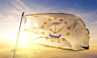 The state flag of Rhode Island with the sun shining behind it