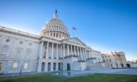 A wide shot of the front of the US Capitol building with an American flag flying