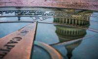 The dome of the U.S. Capitol Building reflected in a puddle on top of a compass rose