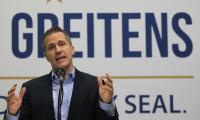 Eric Greitens giving a speech in front of a large sign that says "Greitens".
