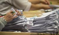 A woman's hands counting a stack of ballots