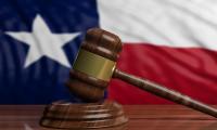 A gavel in front of the state flag of Texas