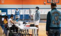 A women with a mask checks in at a polling place inside a school gym