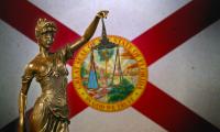 A statue of lady justice in front of the state flag of Florida