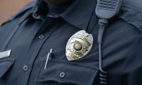 The upper body of a police officer in uniform wearing a badge